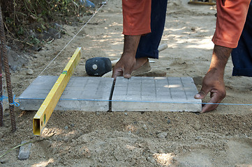 Image showing Worker puts sidewalk tiles