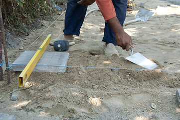 Image showing Worker puts sidewalk tiles