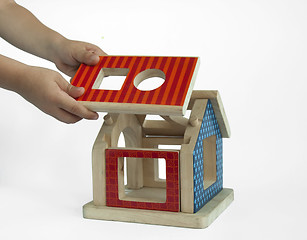 Image showing Boy hands and wood colorful house toy 