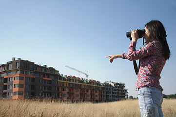 Image showing Woman watching with binoculars building construction