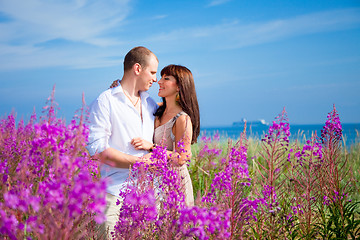 Image showing Romace among purple flowers near blue sea