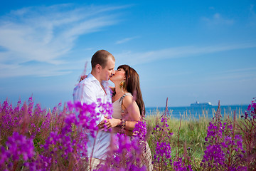 Image showing Romantic kiss among purple flowers near blue sea