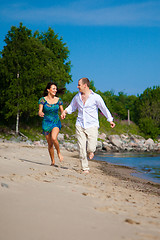 Image showing Enamored couple running along the coast of sea