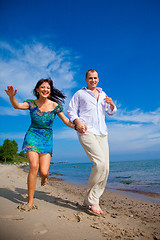 Image showing Enamored couple running along the coast of sea