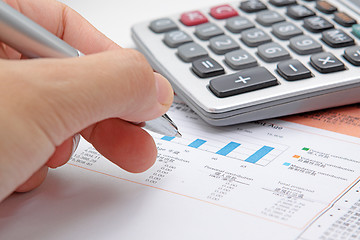 Image showing Businessman's hand showing diagram on financial report with pen.