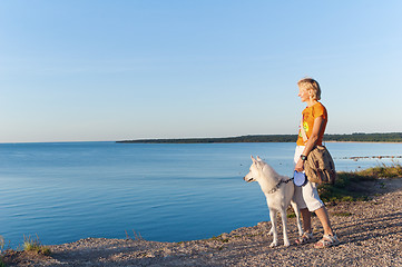 Image showing The woman with a dog costs on edge of breakage at the sea