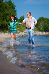 Image showing Enamored couple running along the coast of sea