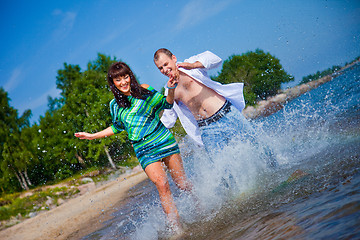 Image showing Enamored couple running along the coast of sea