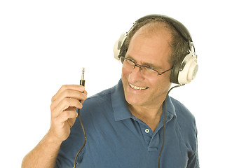 Image showing senior man wearing music head phones looking at plug