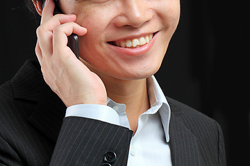 Image showing portrait of e young man talking on mobile against a black backgr