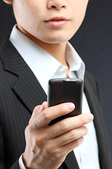 Image showing business man in black suit working on pda or smartphone 