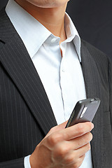 Image showing business man in black suit working on pda or smartphone 