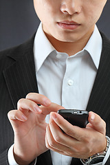 Image showing business man in black suit working on pda or smartphone 