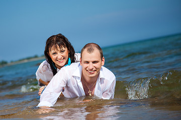 Image showing Enamored man and girl lying in waves of sandy beach