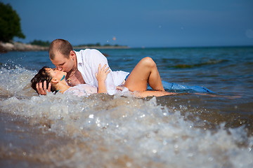 Image showing Enamored man and girl kissing in waves of sandy beach