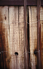 Image showing Old board fence with rusty nails and a barbed wire