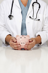 Image showing Doctor with Caring Hands on a Piggy Bank