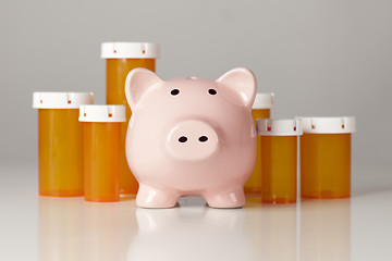 Image showing Piggy Bank In Front of Several Medicine Bottles