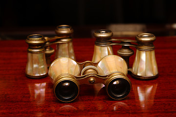 Image showing Three binoculars on a brown desk