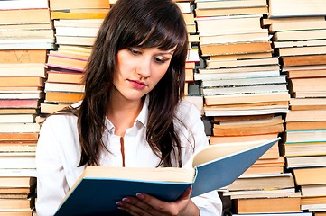 Image showing Beautiful young student girl reading from a big book