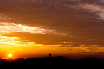 Image showing Evening scene of an urban area with red clouds and silhouettes o