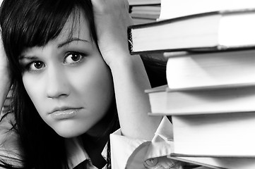 Image showing Young student girl holding her head behind a lot of books