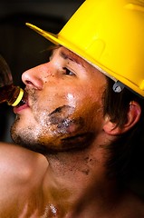 Image showing Industrial worker with oil on his face drinking after job