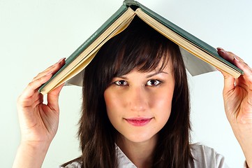 Image showing Beautiful young girl hiding under book