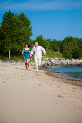 Image showing Enamored couple running along the coast of sea