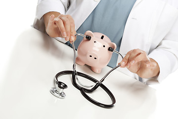 Image showing Doctor Holds Stethoscope to Ears of Pink Piggy Bank