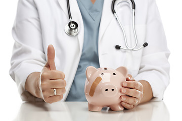 Image showing Doctor with Thumbs Up Holds Hand to Bandaged Piggy Bank