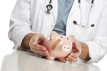 Image showing Doctor Holding Caring Hands on a Piggy Bank with Bandage