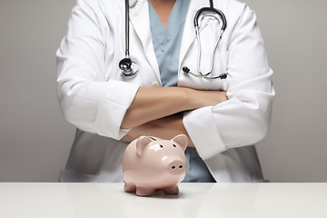 Image showing Doctor with Folded Arms Behind Piggy Bank