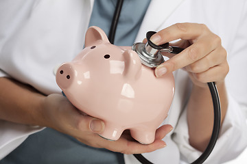 Image showing Doctor Holding Stethoscope to Piggy Bank