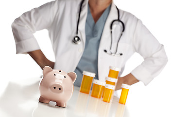 Image showing Doctor Standing Behind Medicine Bottles and Piggy Bank