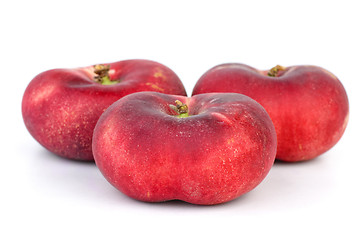 Image showing Three red flat peaches 