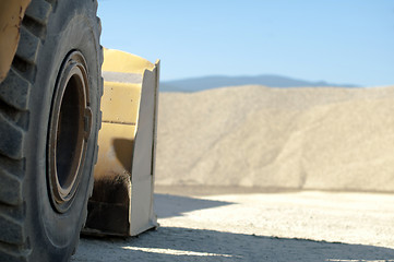 Image showing Tire backhoe close-up and piles of sand 