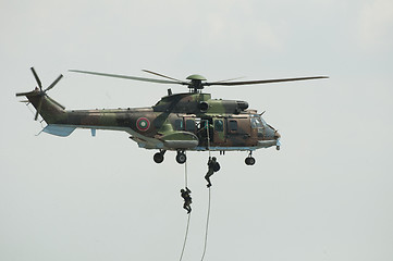 Image showing Two soldiers hanging from a helicopter