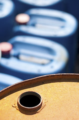 Image showing Old colored oil barrels and blue canisters