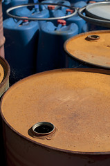 Image showing Old colored oil barrels and blue canisters