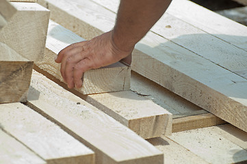 Image showing Worker moves a wooden beam