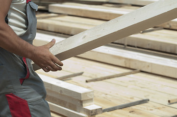 Image showing Worker moves a wooden beam
