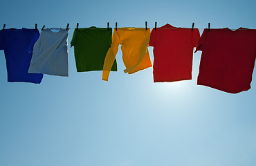 Image showing Sun shining through colorful clothes drying in the wind