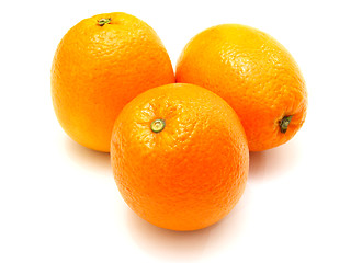 Image showing Three ripe oranges lie nearby on a white background