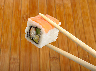 Image showing sushi in wooden chopsticks