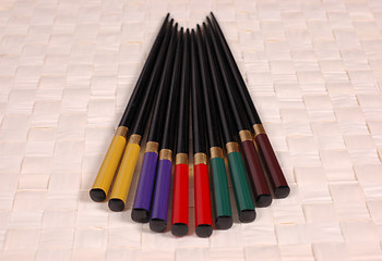 Image showing Multi colored chop sticks on mat