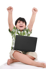 Image showing Happy little boy with laptop with moving apart his hands - indoo