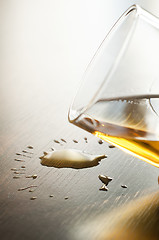 Image showing Glass with whiskey and drops on the table