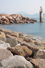 Image showing Lighthouse on a Rocky Breakwall: A small lighthouse warns of a r