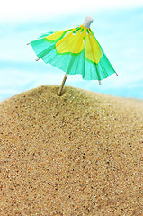 Image showing cocktail umbrella on sand